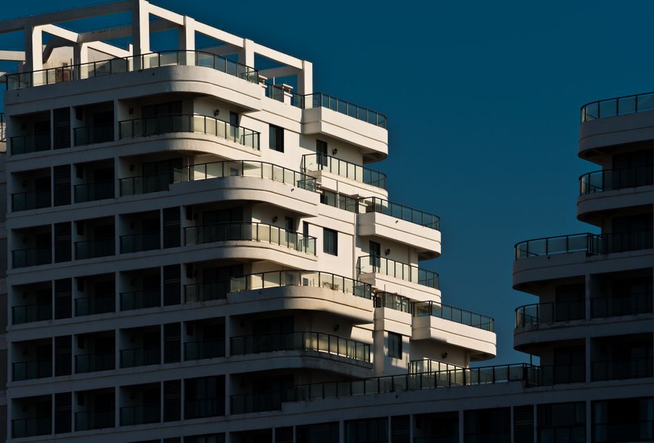 Stunning view of a modern apartment building with glass balconies at sunset.
